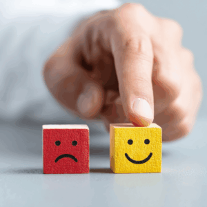 Main choisissant un cube jaune avec un sourire à côté d’un cube rouge triste, symbolisant le rebond et la transition de carrière réussie