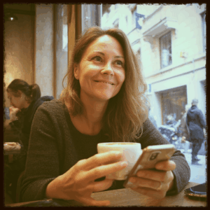 Femme souriante tenant une tasse de café dans un café, moment de pause et de douceur.