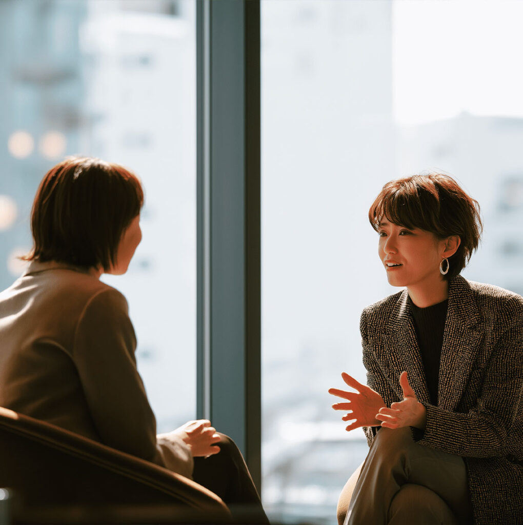 Deux personnes discutant en face à face dans un cadre professionnel, illustrant la communication et les réactions nerveuses lors d’un entretien d’embauche.