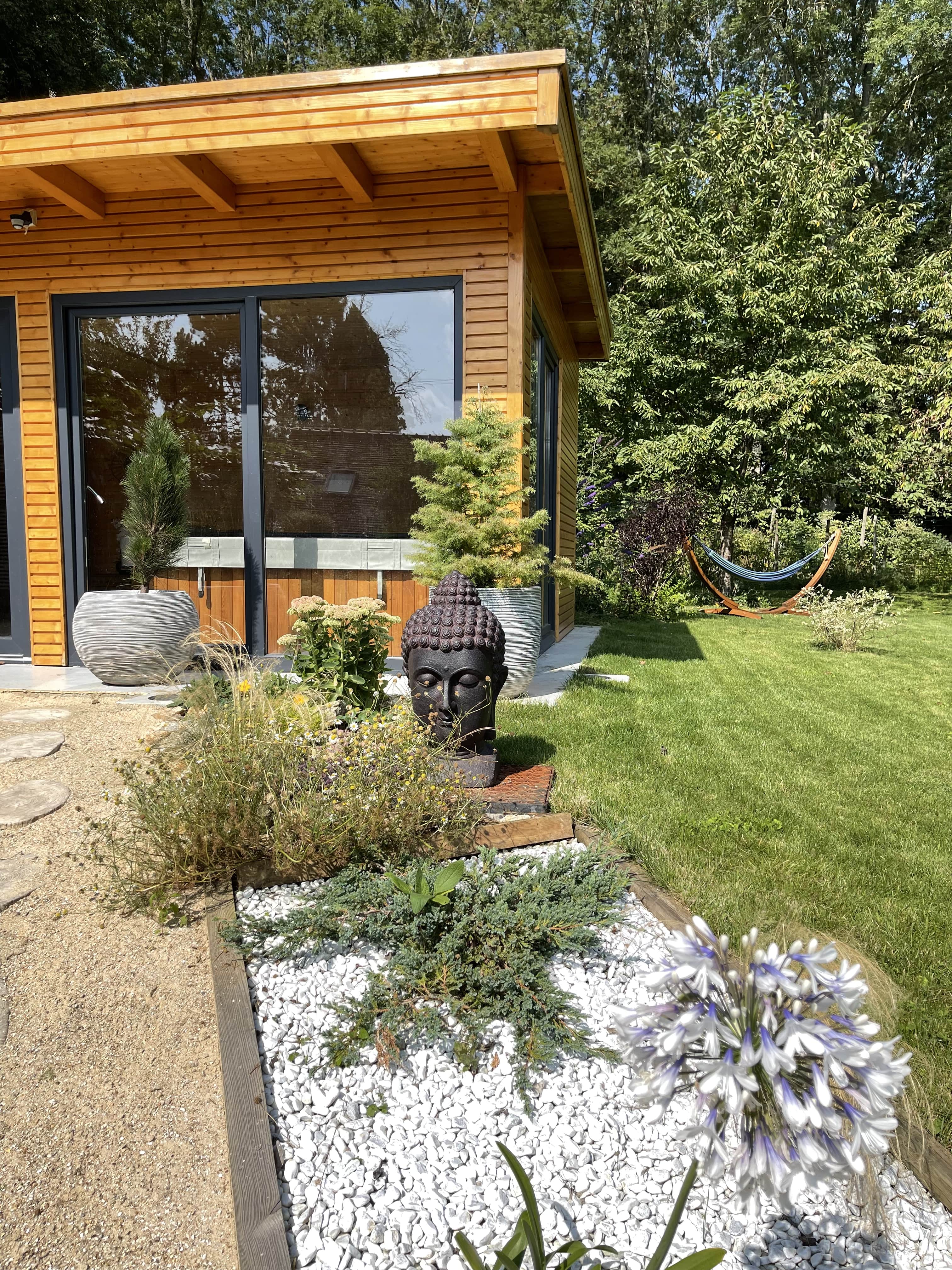 Espace zen du domaine Osélience avec spa en bois, statue de Bouddha et jardin apaisant pour des séjours bien-être.