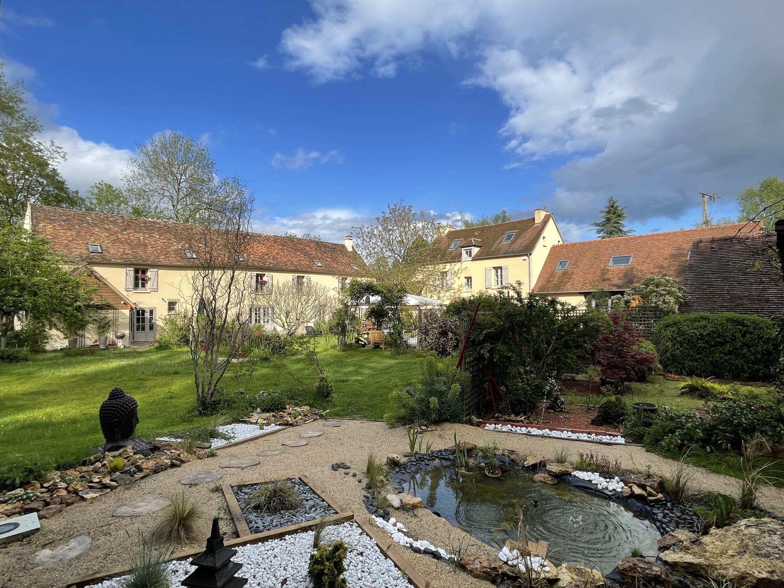 Vue du domaine Osélience avec jardin paysager, bassin et maison en pleine nature
